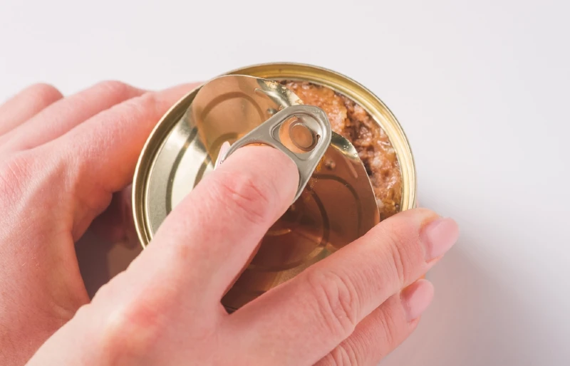 close up of persons hands opening a can-of wet pet food