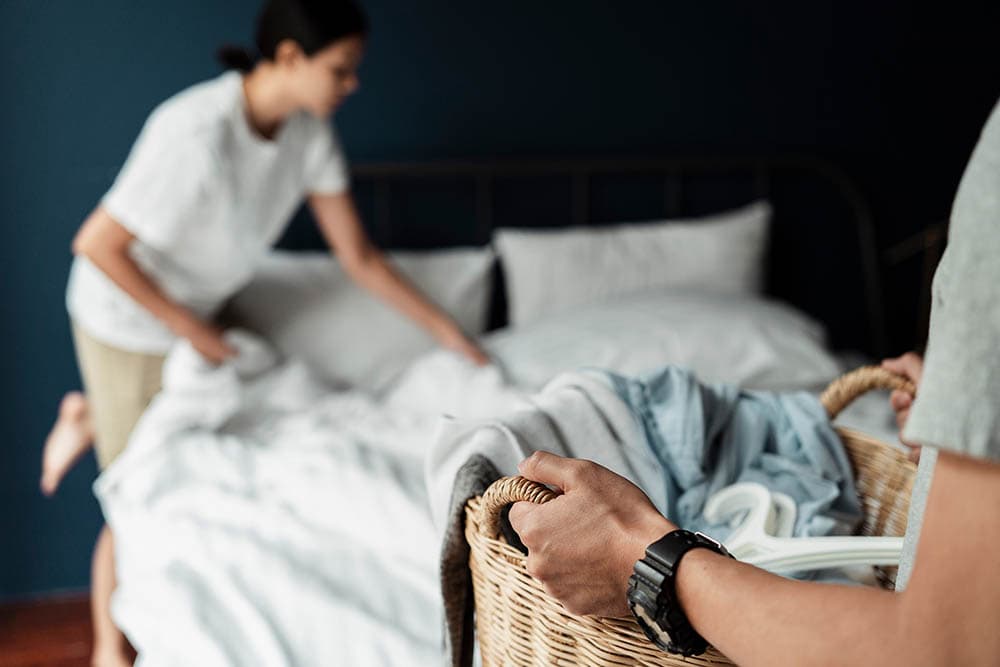 couple removing beddings for laundry