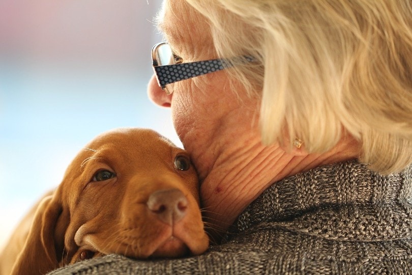 elderly woman huggine a puppy