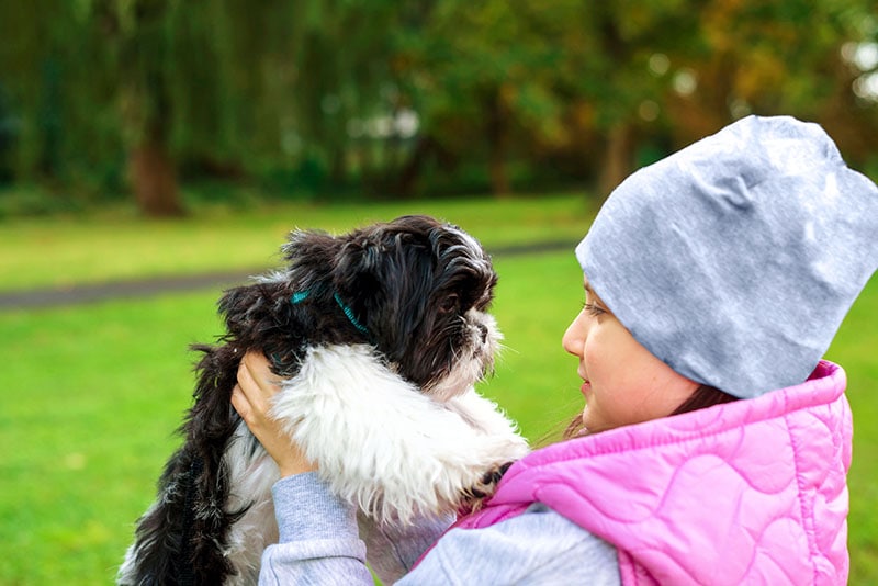 girl child carrying a shih tzu