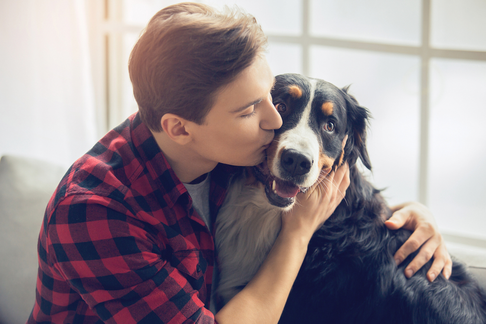 male owner hugging and kissing his pet dog