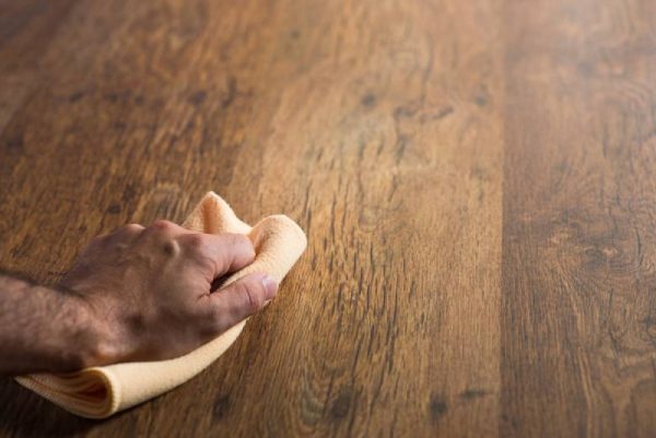 man cleaning hardwood floor with microfiber cloth