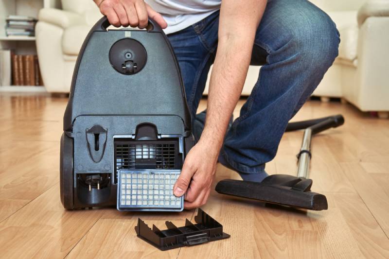 man replacing an air filter of a vacuum cleaner at home