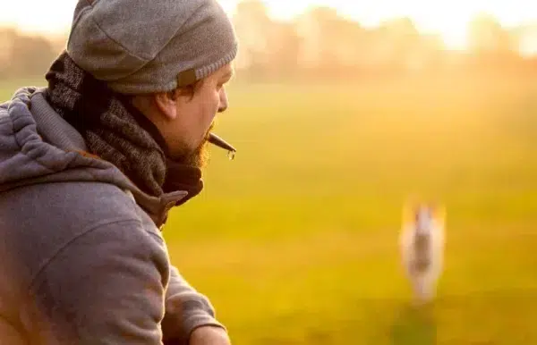 man training his pet with a dog whistle