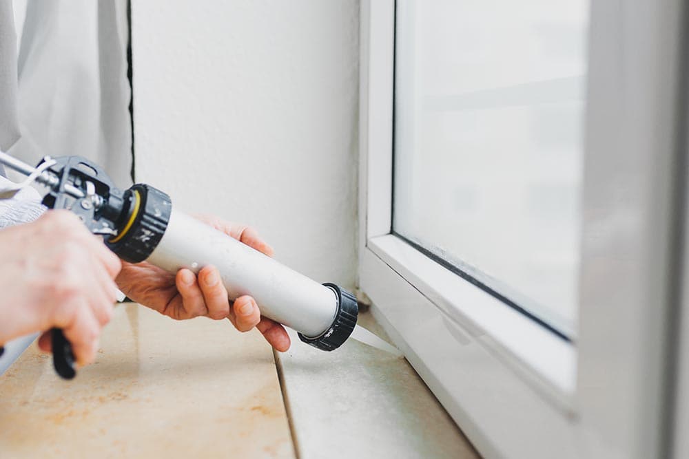 person caulking the window