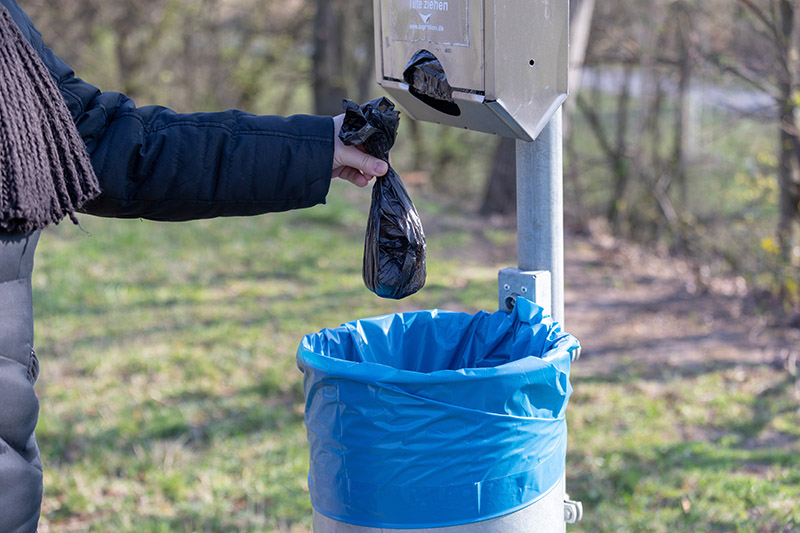 person disposing poop waste in trash can