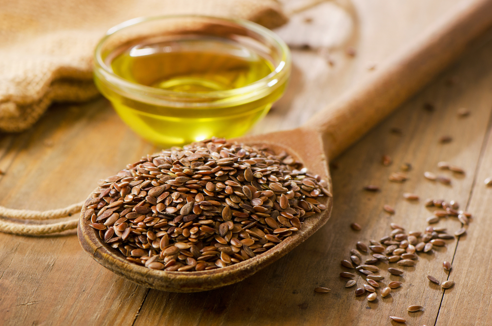 Brown flax seeds on a spoon and flaxseed oil