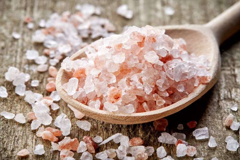 spoon of pink himalayan rock salt on wooden table