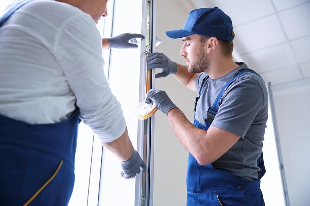 two men weatherstripping the door