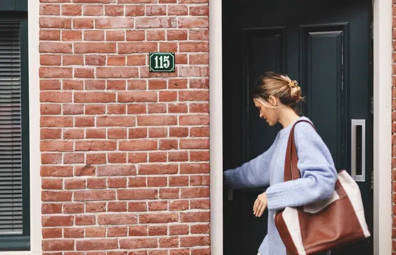 woman closing or opening the door to a house