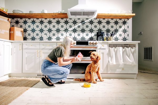 woman feeding dog with nom nom beef mash