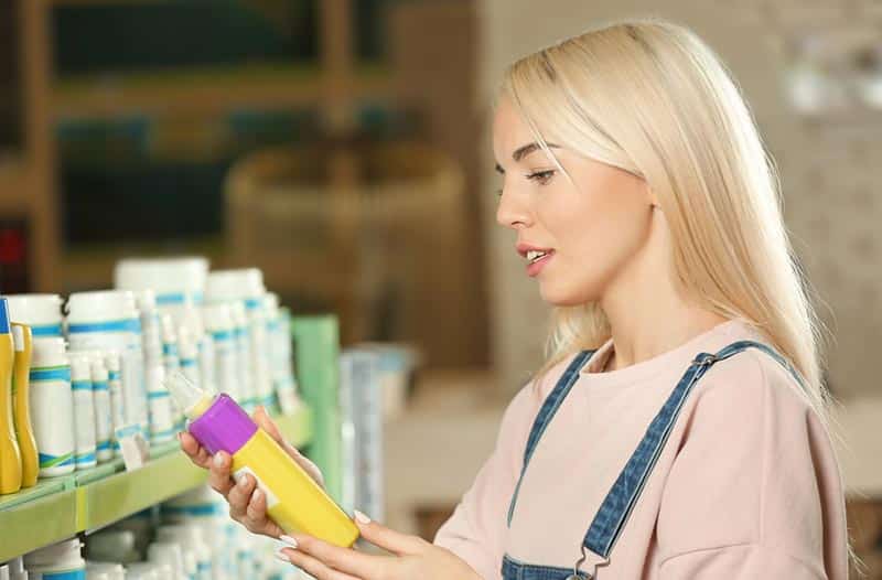 woman selecting shampoo or conditioner in a pet store