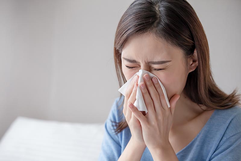 woman sneezing on a tissue paper