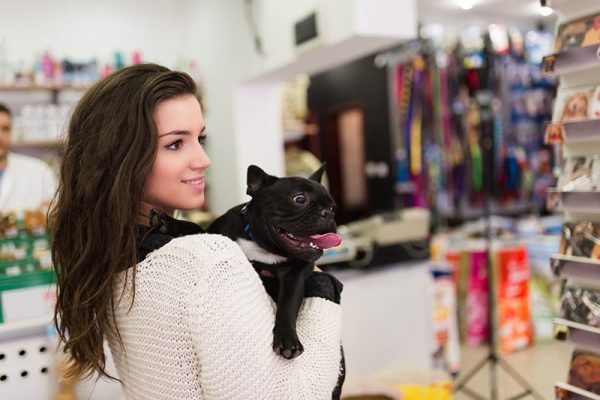 woman with her French bulldog puppy in pet shop