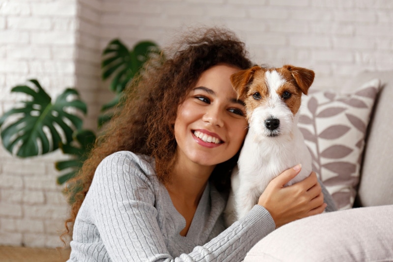 young-woman-hugging-her-jack-russel-terrier-puppy-at-home