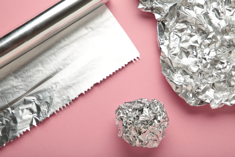 Foil ball with aluminium rolls on pink background. Top view