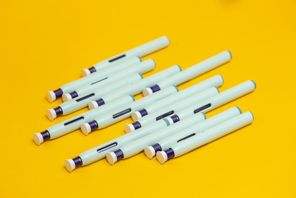 Couple of graphically organized syringe pens on seamless yellow background