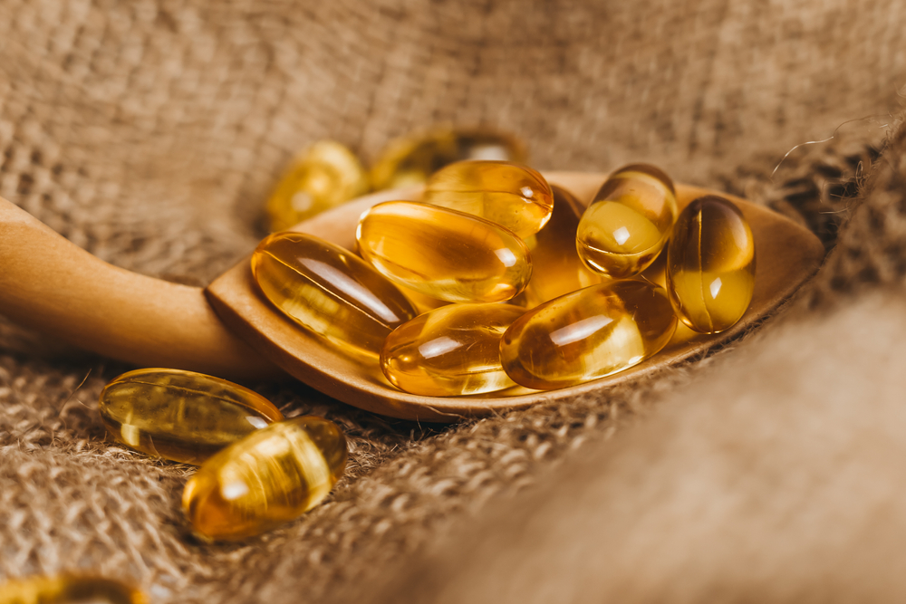 Fish oil capsules on a wooden spoon