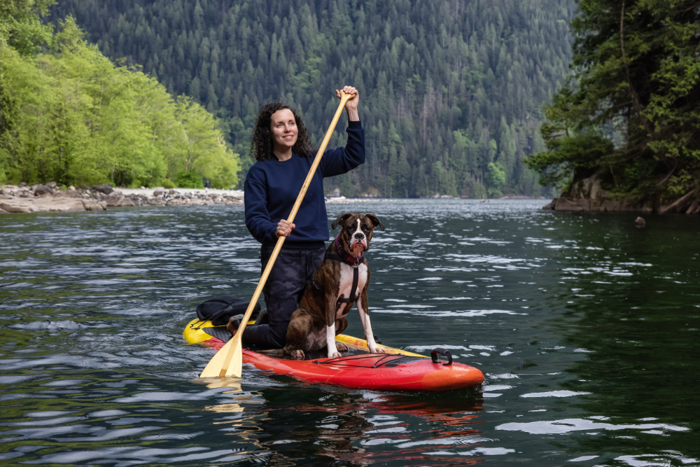 Woman on a paddle board with boxer dog