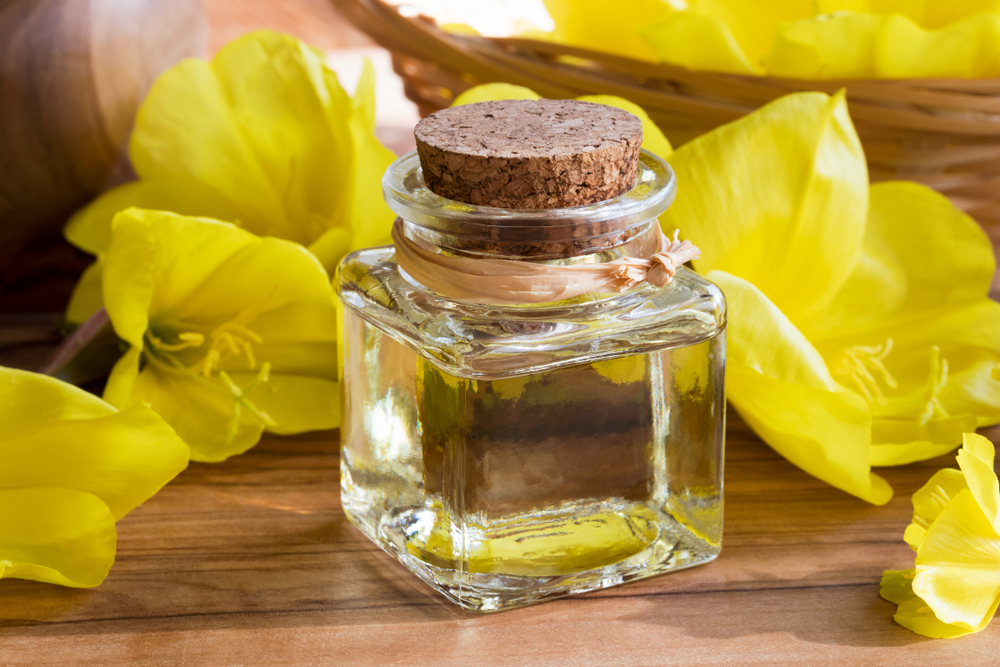 bottle of evening primrose oil with fresh evening primrose flowers in the background