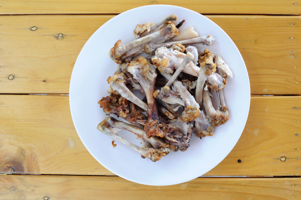 chicken bones on a plate on top of wooden table