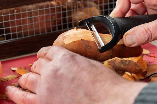 hand peeling a raw sweet potato