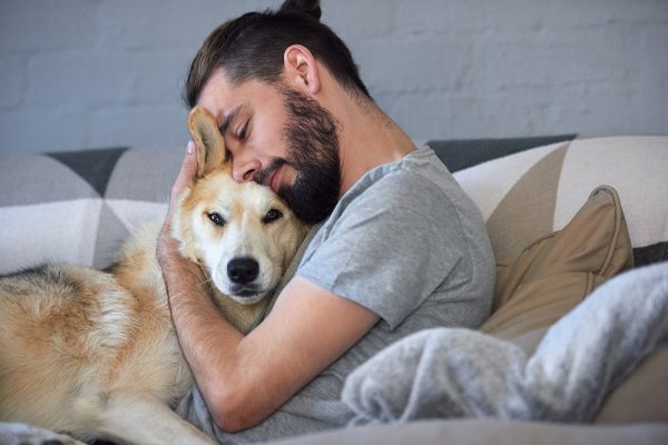 hipster man snuggling and hugging his dog