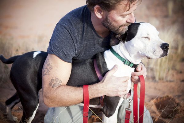 man with paw tattoo hugging his dog