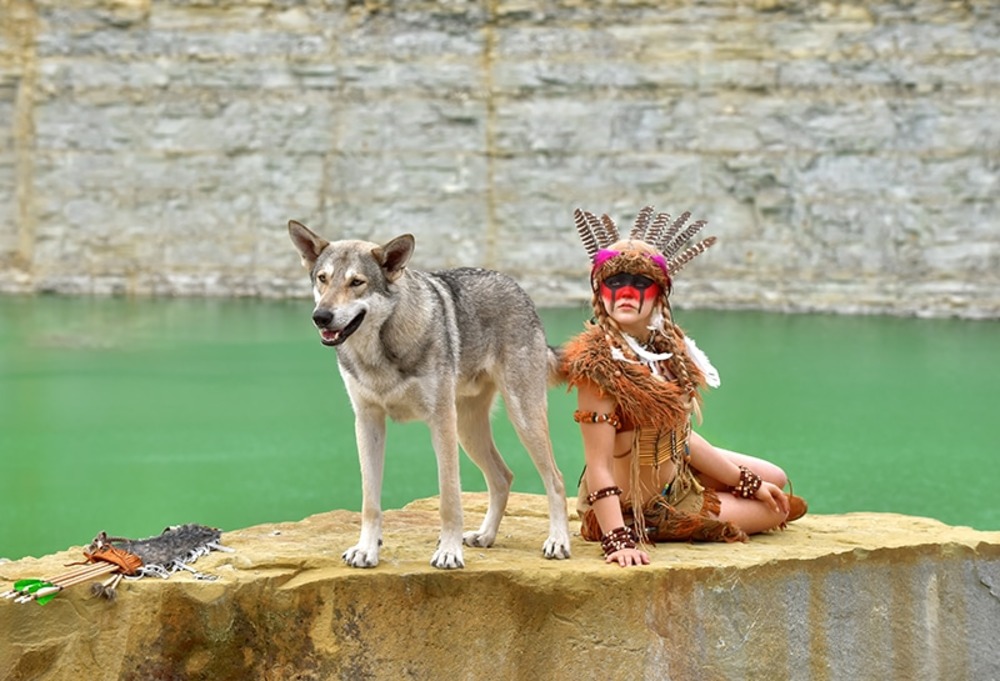 native american indian dog standing beside a sitting woman wearing native clothes