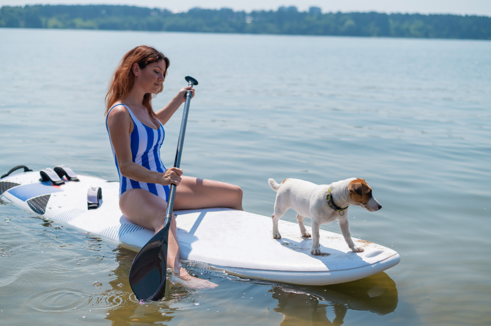 woman is riding a surfboard with a dog