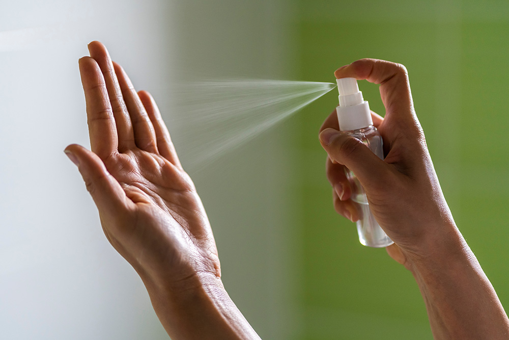 Caucasian woman wipes her hands with an alcohol-based hand-washing spray