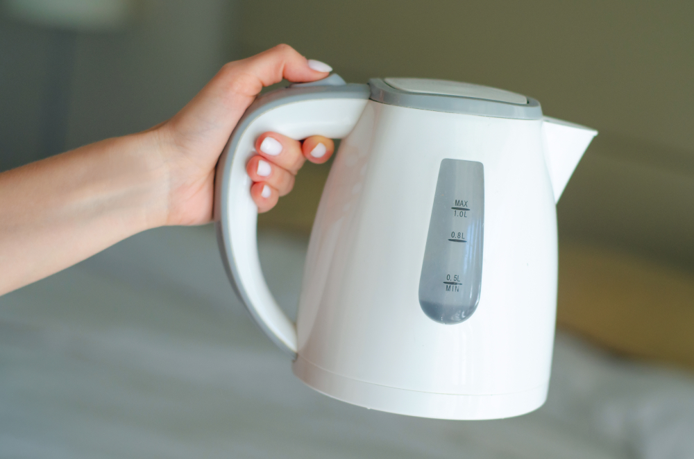 Women hand hold the plastic electric kettle preparing hot water