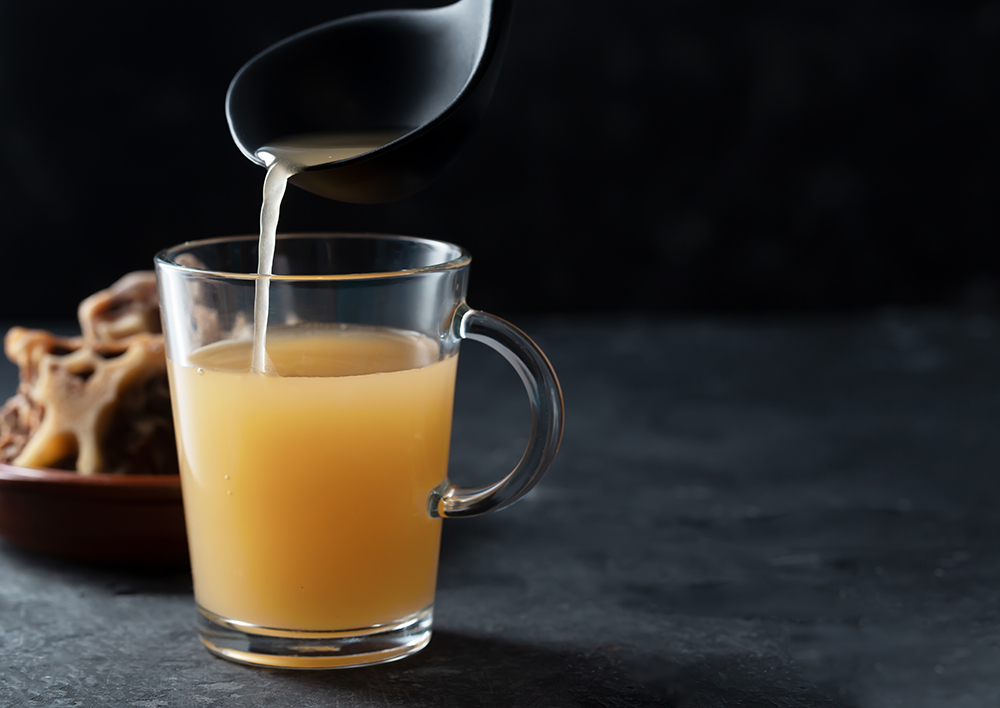 pouring homemade broth to a glass