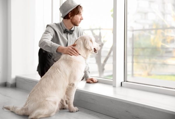 young man with his pet dog looking out the window