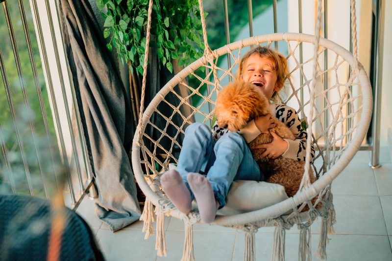 Little kid hugging a poodle dog at home on the balcony in spring